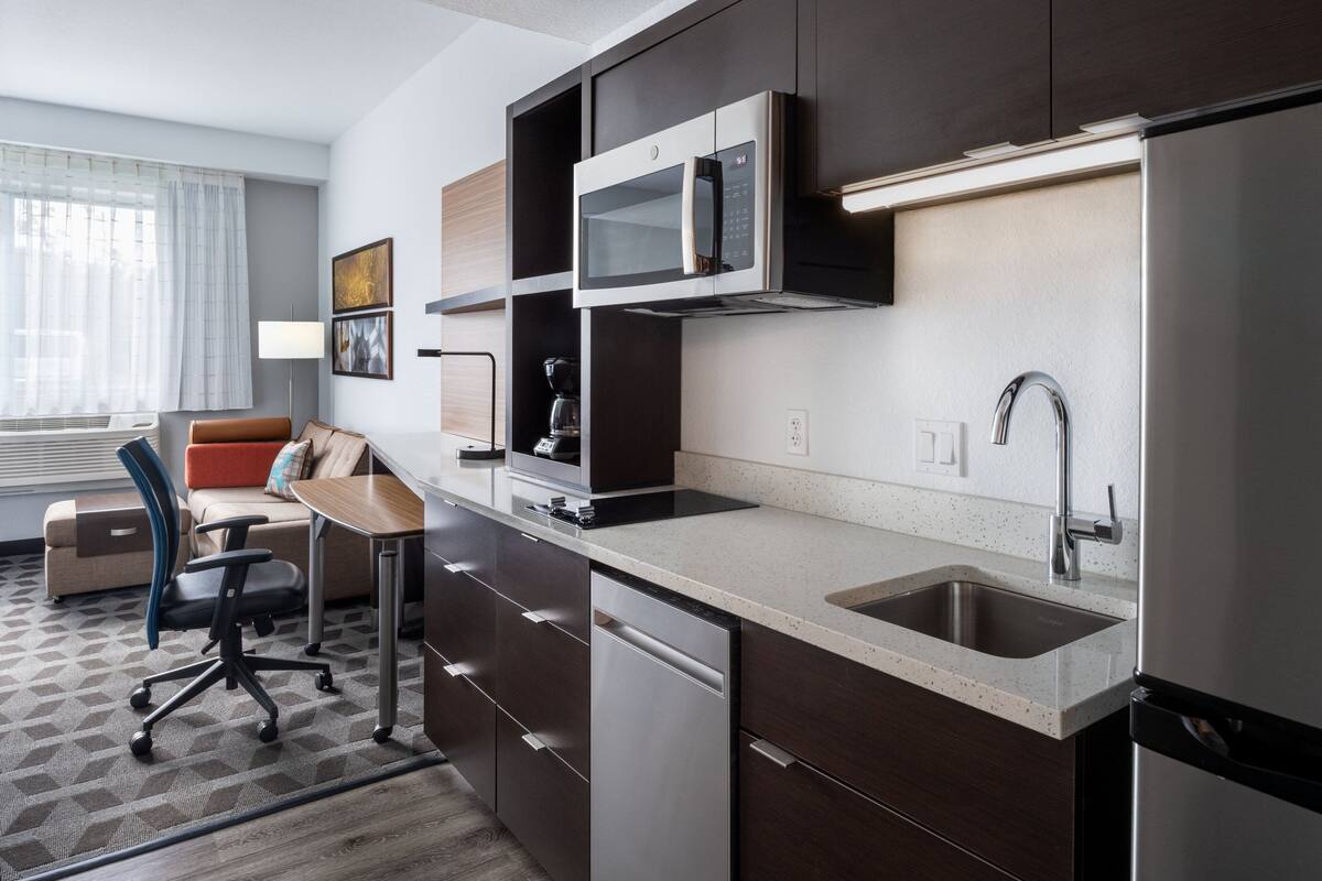 A modern kitchen with a built-in microwave, stainless steel sink, and dishwasher.