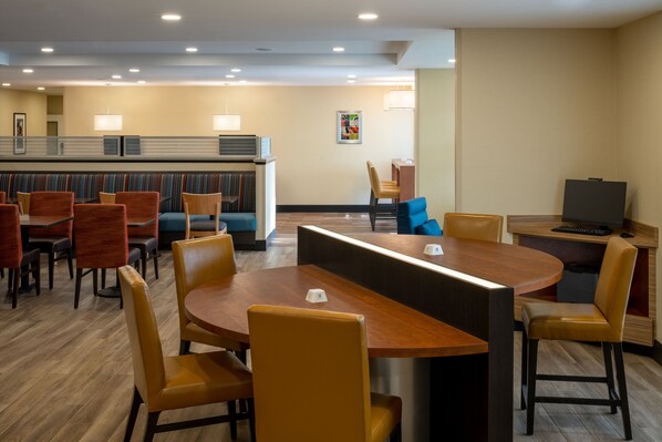 A hotel lobby with a reception desk, seating area with tables and chairs, and a television on a desk. - TownePlace Suites by Marriott Venice (Venice)