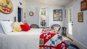 A bedroom with a bed, a quilt, a clock, and various wall decorations.