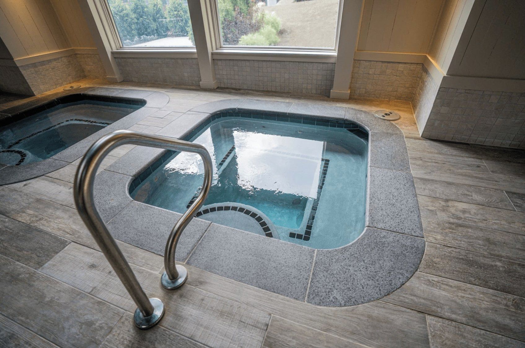 A spa area with two hot tubs and a metal ladder.