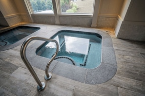A spa area with two hot tubs and a metal ladder.
