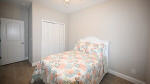 A bedroom with a bed, a ceiling fan, and a door. - Seaglass Cottages (calabash)