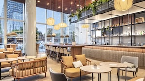 A modern bar area with seating, large windows, and indoor plants.