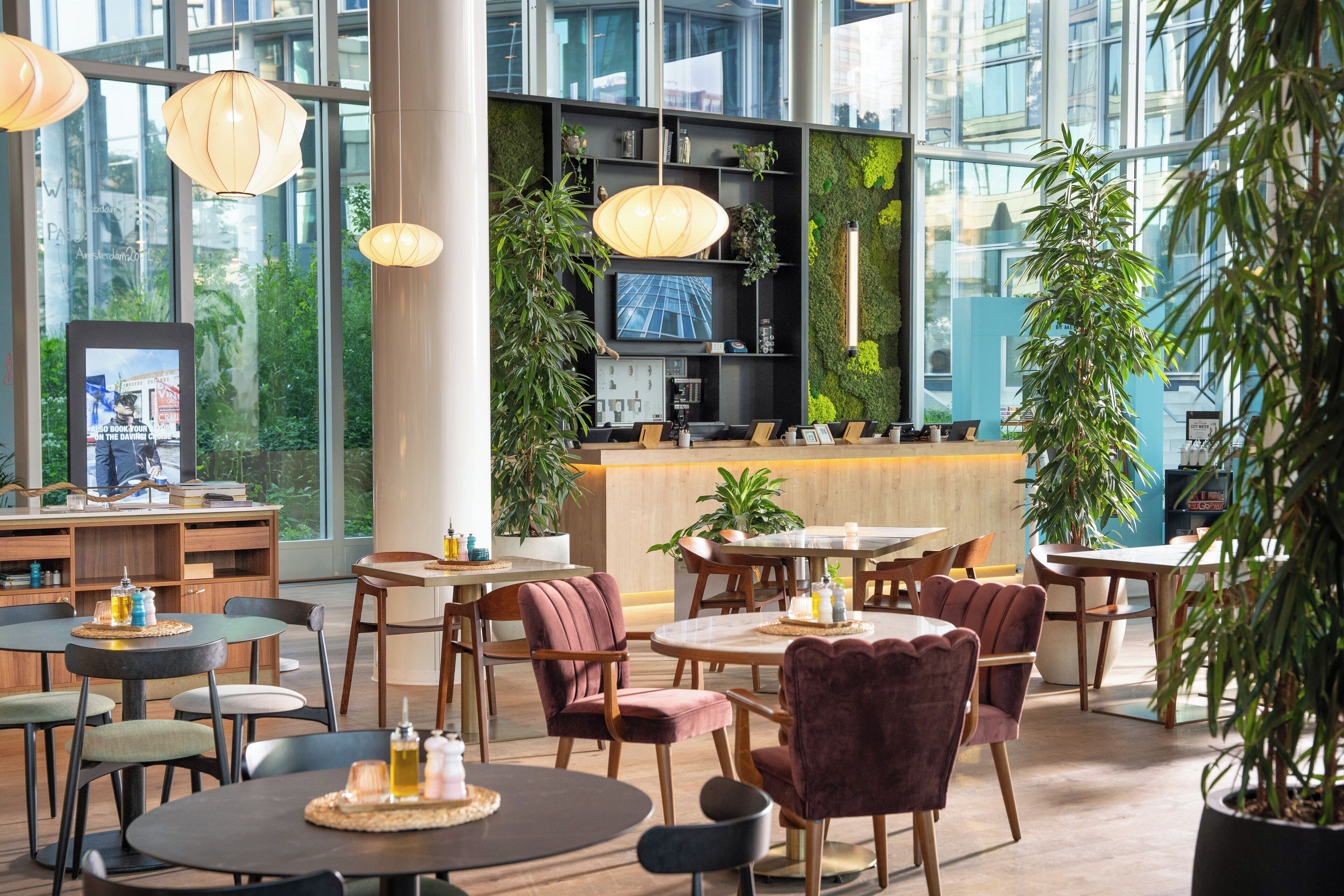 Un espacio interior moderno con mesas, sillas, una zona de recepción y ventanas amplias.
