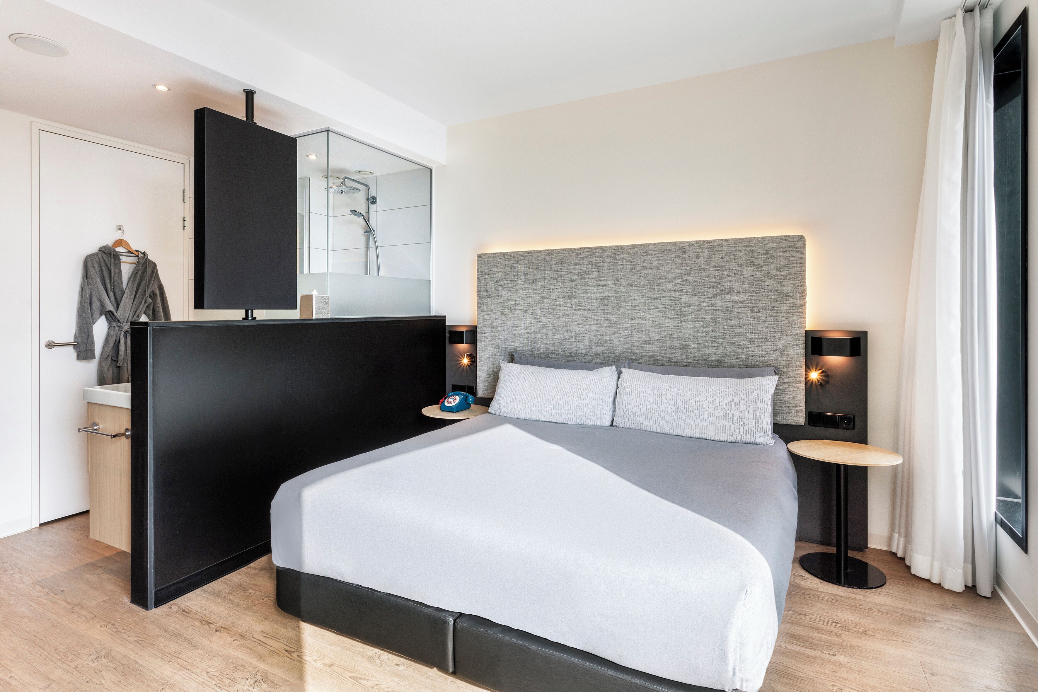Een moderne hotelkamer met een groot bed, nachtkastjes, een kledingkast en een douche.