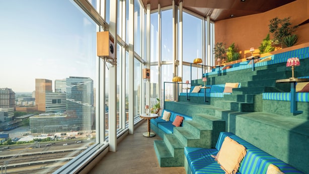 A modern interior with a view of the city, a staircase, and a seating area.