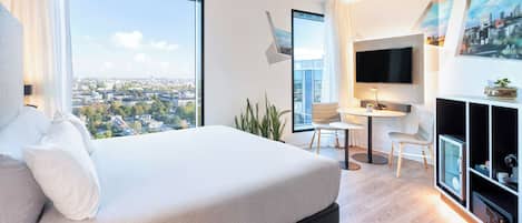 Une chambre d’hôtel moderne dotée d’un grand lit, d’un bureau, d’une télévision et offrant une vue sur la ville.