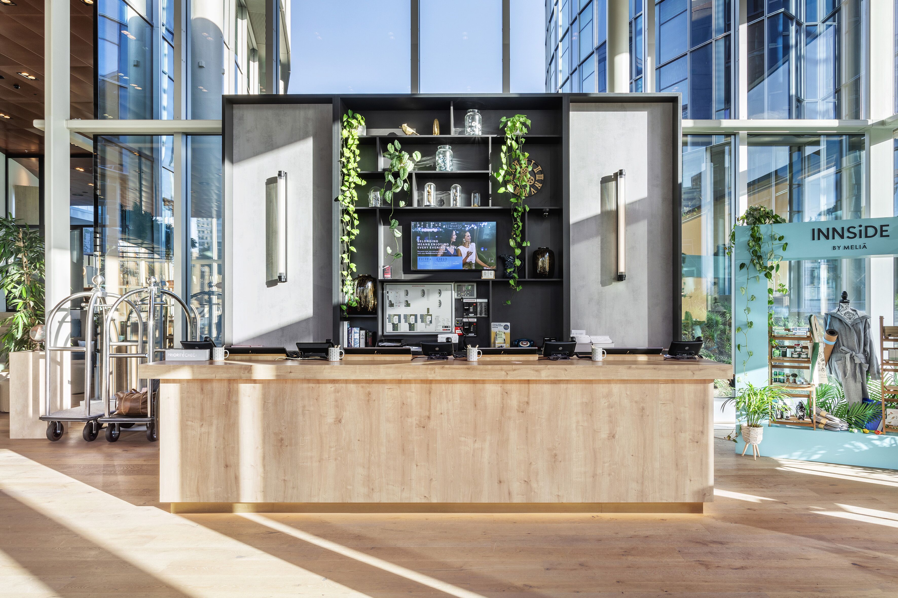 A modern reception desk with a wooden counter, a television screen, and shelves with decorative items.