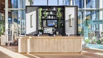 A modern reception desk with a wooden counter, a television screen, and shelves with decorative items.