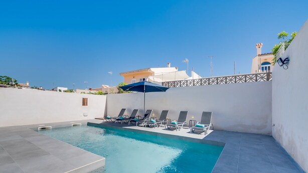 Une piscine sur le toit, dotée de chaises longues et d’un parasol bleu.