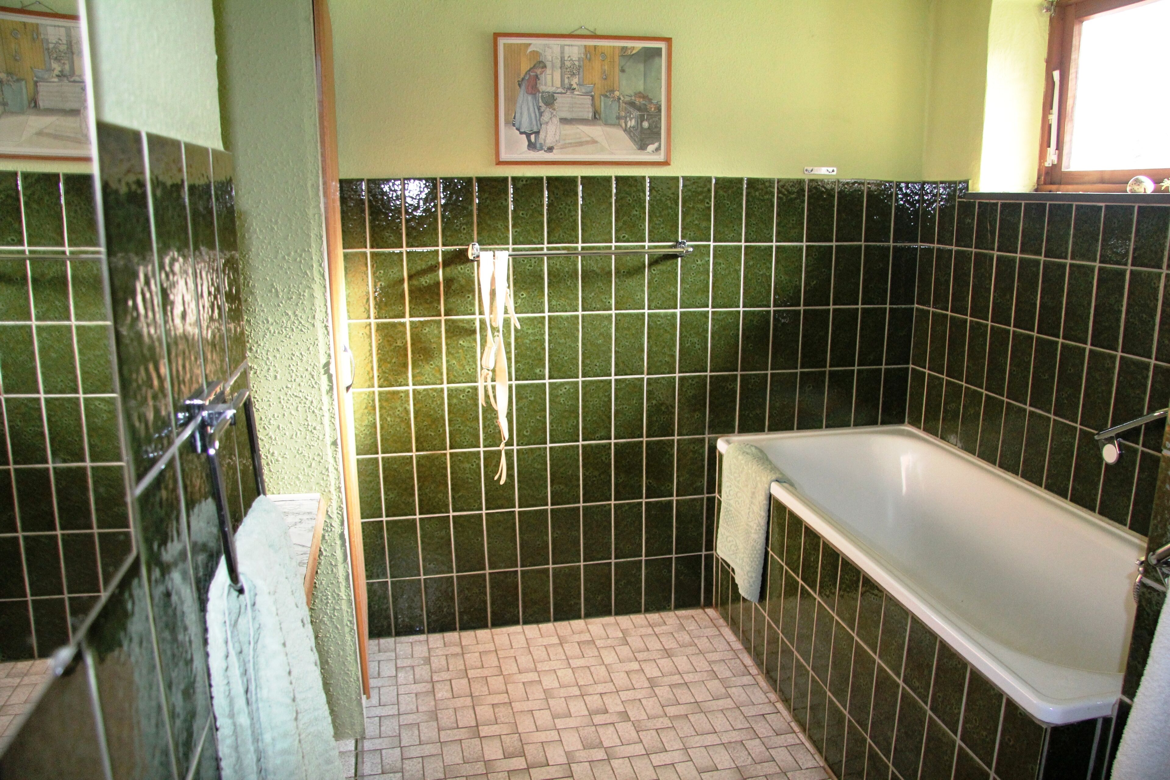 A bathroom with a bathtub, a shower, and a tiled wall.