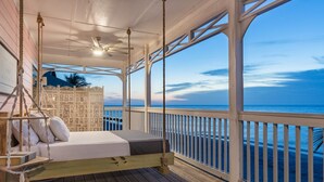 A wooden deck with a bed and a ceiling fan, overlooking a beach. - Pink Flamingo Beach House Private Beachfront Paradise with Pool Sleeps 12 (North Captiva)