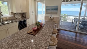 A kitchen with a large island, a dining area with a view, and a sliding glass door to the outside. - Pink Flamingo Beach House Private Beachfront Paradise with Pool Sleeps 12 (North Captiva)