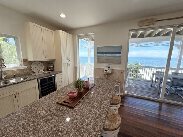 Una cocina con una isla grande, un comedor con vistas y una puerta corrediza al exterior.