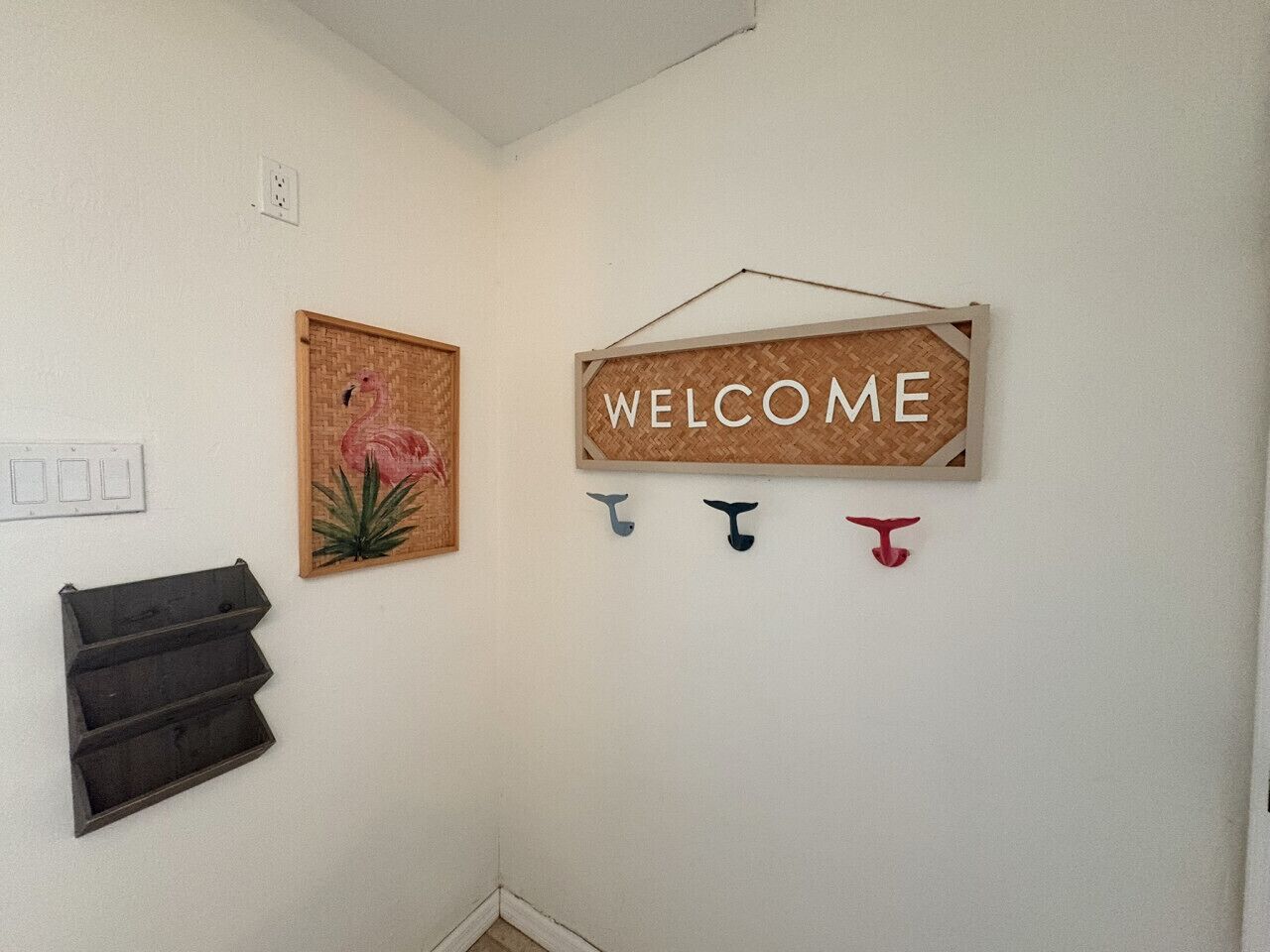 Eine Wand mit einem Willkommensschild, einem Flamingo-Bild und einem schwarzen Stauraum.