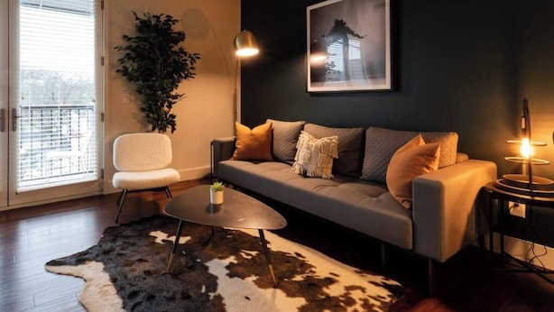 A modern living room with a sofa, a coffee table, a chair, and a large plant. - Coffee Shops, Restaurants, Bars, Salons and Boutiques, just steps away. (Nashville)