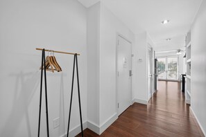 Un pasillo con un perchero de madera, paredes blancas y suelo de madera.