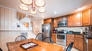 A kitchen with wooden cabinets, stainless steel appliances, and a dining area with a wooden table and chairs.