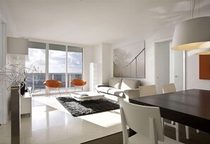 Relax in this stylish living room with a large window, comfortable sofa, and a dining table for meals.