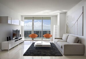 Relax in this spacious living room with a sofa, two comfortable chairs, and a flat-screen TV.