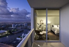 Enjoy a city view from the balcony, featuring a bed, bedside table, and chair.
