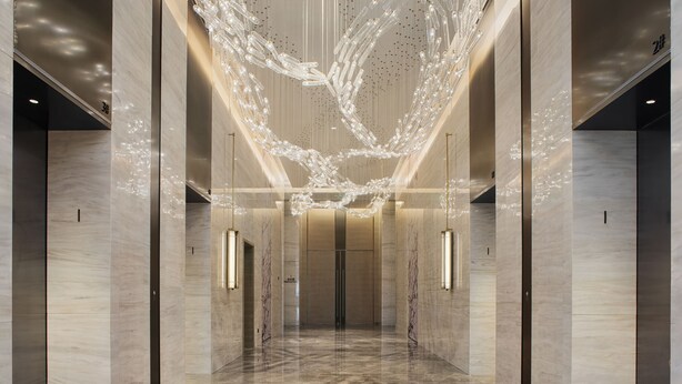 A modern lobby with a reflective marble floor, a central light installation, and a symmetrical design with elevators on either side. - InterContinental Foshan Dongping Hotel by IHG (Foshan)