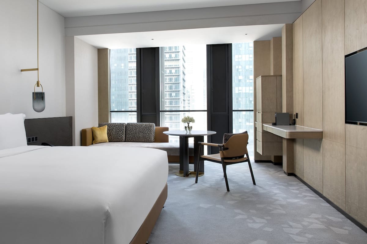 A hotel room with a large bed, a small dining area, and a TV mounted on the wall.