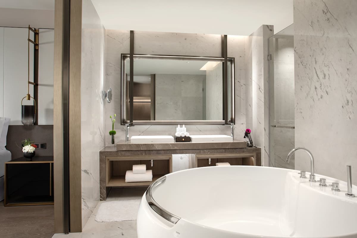 A modern bathroom with a large bathtub, a double sink vanity, and a large mirror.