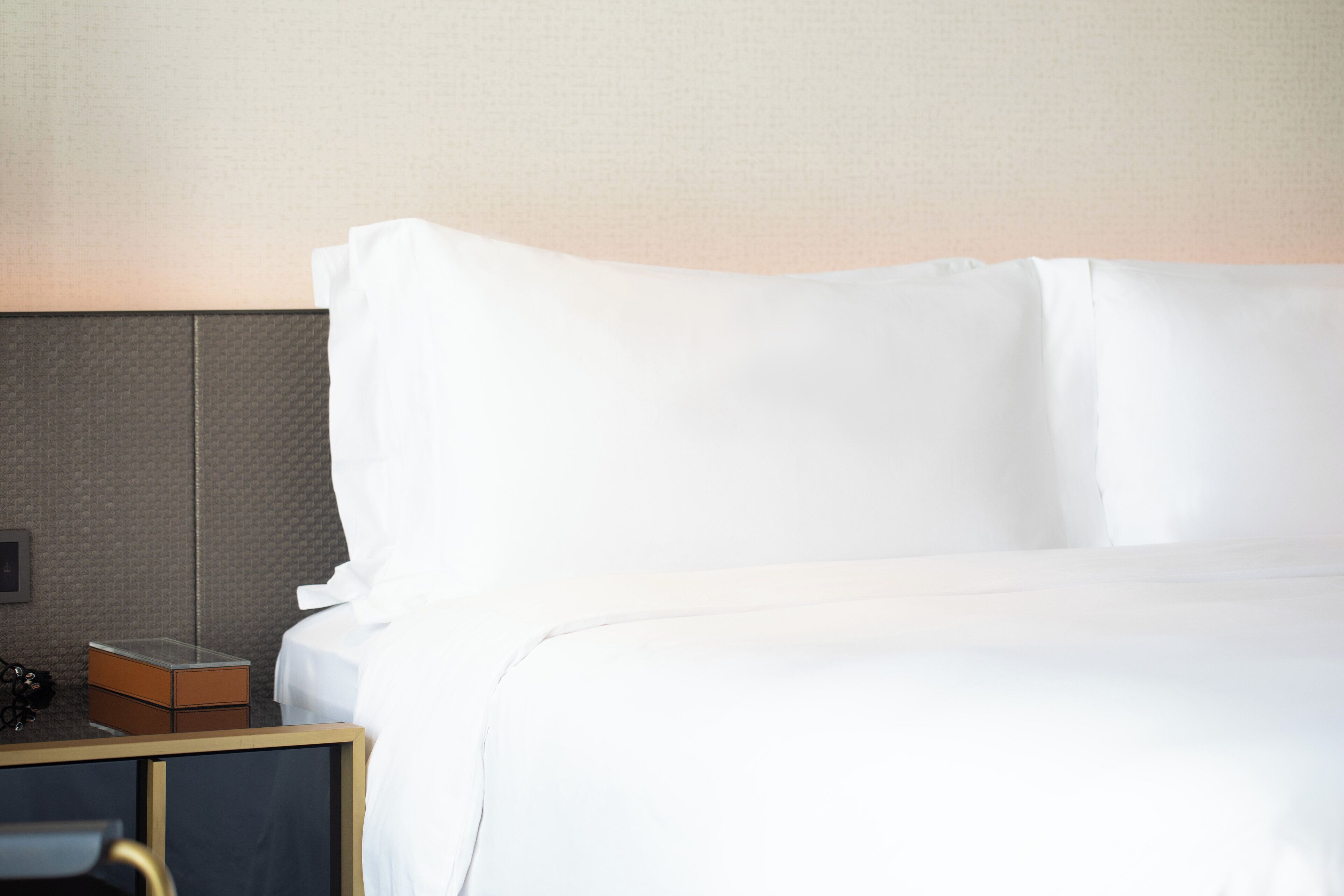 Een net opgemaakt bed met witte lakens in een hotelkamer.