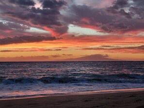 A beach with waves and a sunset.