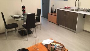 Een compacte keuken met een eethoek, een tv boven de tafel en een klein raam.