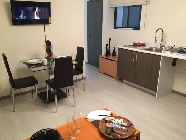Une cuisine compacte avec un coin repas, un téléviseur fixé au-dessus de la table et une petite fenêtre.