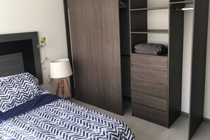 A bedroom with a bed, a bedside lamp, a wardrobe, and a small table with a lamp. - Home Office and vacation 2Br near condesa and polanco (Mexico City)