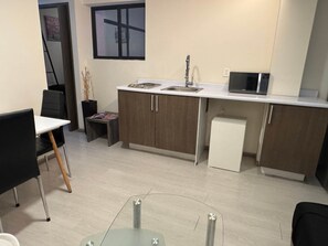 A compact kitchen with a microwave, sink, and cabinets.