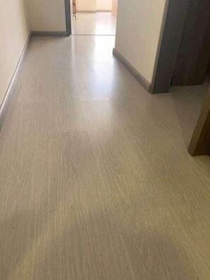 A hallway with a light-colored floor and a door at the end.