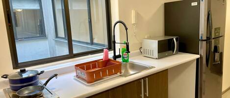 Kylskåp, mikrovågsugn, spishäll och grytor/köksredskap