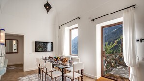 Un coin repas avec une table en verre, des chaises blanches et un tapis à motifs.