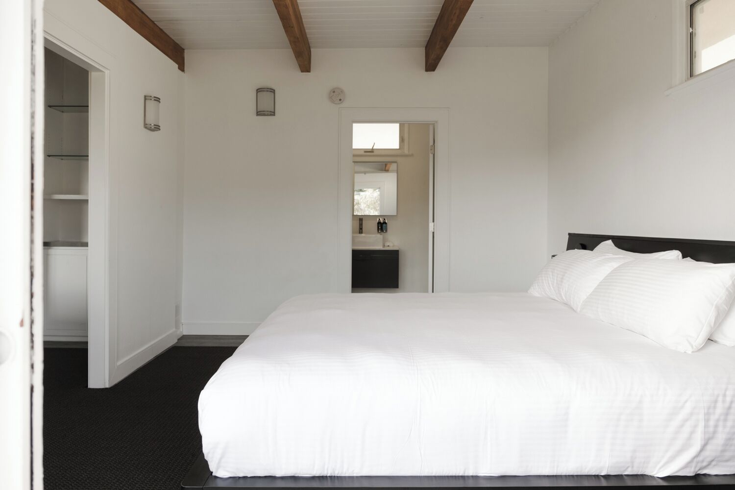 A bedroom with a large bed, a wardrobe, and a mirror.