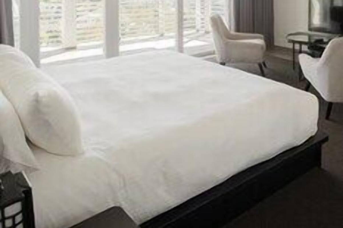 A hotel room with a large bed, a desk, a chair, and a TV.