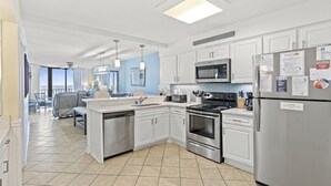 A modern kitchen with white cabinets, stainless steel appliances, and a large island.