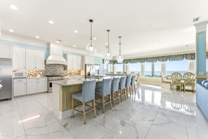 A modern kitchen with a central island, stainless steel appliances, and a view to the sea.