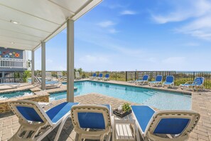 A poolside area with lounge chairs and a view of the ocean.