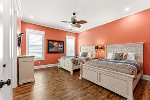 A bedroom with two beds, a ceiling fan, and a painting on the wall.