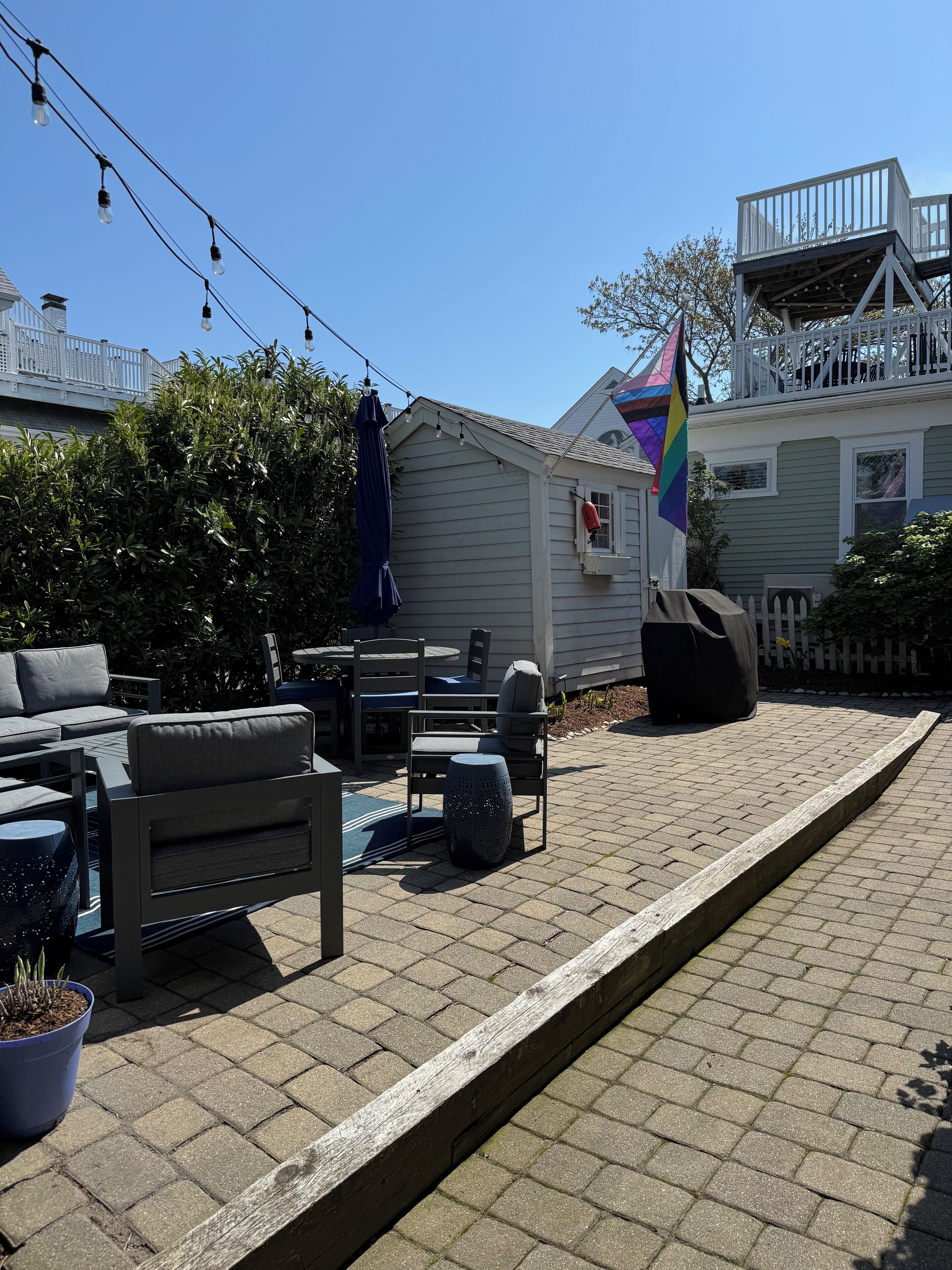 A patio area with outdoor furniture, a flag, and a house in the background.