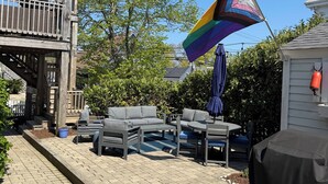 A patio area with outdoor furniture, a flag, and a building with a balcony. - Amazing WEST END location, steps away from all the action! (Provincetown)