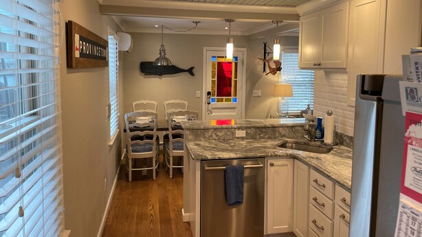 A kitchen with white cabinets, a stainless steel refrigerator, and a marble countertop. - Amazing WEST END location, steps away from all the action! (Provincetown)