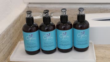 Quatre bouteilles de produits Cayan Cancun présentées sur un plateau blanc.