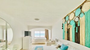 Una habitación de hotel moderna con una cama grande, televisión, escritorio y vista al océano.