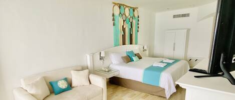 A hotel room with a bed, a sofa, a TV, and a wardrobe.
