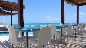 An outdoor dining area with tables and chairs, overlooking a pool and the ocean. - Cyan Cancun Resort & Spa  (Cancun)